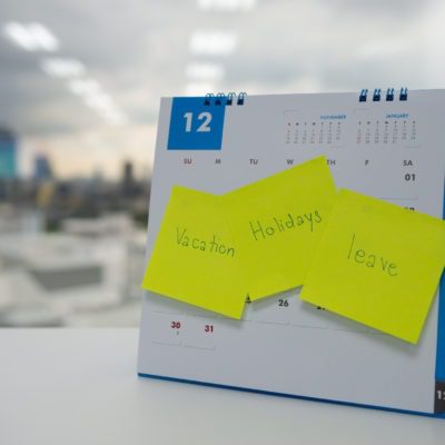 Desk calendar with sticky notes saying "vacation", "holidays", and "leave"
